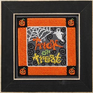 May include: A framed cross-stitch piece with a Halloween theme. The design features the words "Trick or Treat" in orange and yellow, a white ghost, and a spiderweb on a gray background. Orange and black borders with jack-o'-lanterns complete the design.