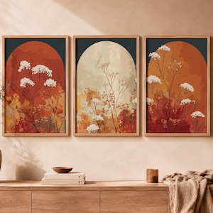 Peut inclure: Un ensemble de trois cadres muraux représentant des formes en arche avec des textures aquarelles abstraites dans des tons terre cuite, orange et crème, superposées de délicates silhouettes florales blanches sur des fonds gris anthracite.
