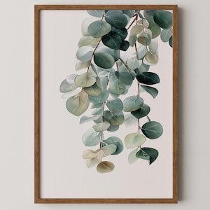 May include: A framed botanical print featuring watercolor eucalyptus leaves in shades of green and gray. The leaves cascade downwards against a pale pink background, encased in a brown wooden frame. A nature-inspired artwork.