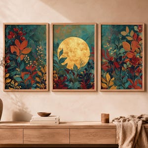 Peut inclure: Un ensemble de trois impressions d'art mural rectangulaires encadrées présentant un thème botanique vibrant avec un feuillage bleu sarcelle profond, orange et rouge. L'impression centrale affiche une grande lune dorée texturée et circulaire.