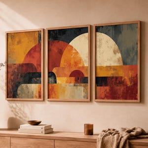 Puede incluir: Un conjunto de tres láminas de arte mural enmarcadas con formas geométricas abstractas en tonos naranja quemado, rojo intenso, azul oscuro y crema. La obra muestra una apariencia texturizada y en capas con semicírculos superpuestos.