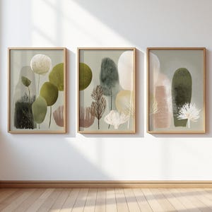 May include: Three framed abstract art prints. Each print features a nature-inspired design with soft colours like olive green, beige, and muted pink. The artwork includes stylised trees and organic shapes, all set against a light green background.