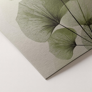 May include: Close-up of a canvas print featuring a botanical design. The artwork showcases stylized green ginkgo leaves with intricate line details against a textured, light gray background. The leaves are arranged in a fan-like pattern.