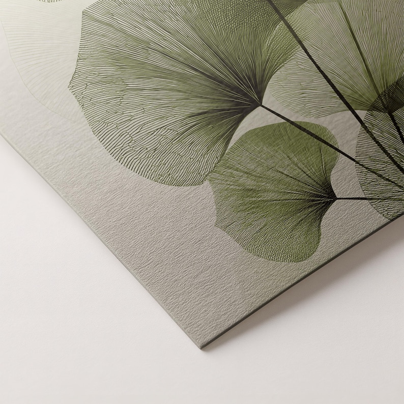 May include: Close-up of a canvas print featuring a botanical design. The artwork showcases stylized green ginkgo leaves with intricate line details against a textured, light gray background. The leaves are arranged in a fan-like pattern.