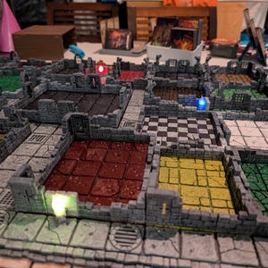 May include: A modular tabletop dungeon terrain set featuring interconnected stone walls and various colored floor tiles including red, yellow, green, black, and white checkered patterns, with small integrated LED lights in blue, red, and green.