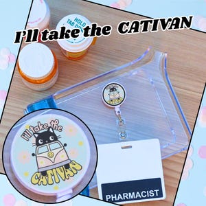 May include: A clear plastic badge holder with a retractable badge reel featuring a cat in a van design and the text "I'll take the CATIVAN". A white badge with "PHARMACIST" printed on it is also visible.