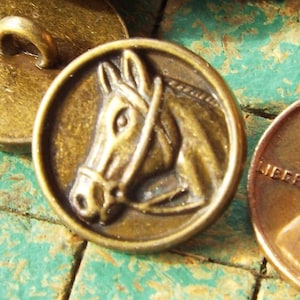 May include: A set of six antique brass buttons featuring a horse head design. The buttons are round and have a loop on the back for sewing.