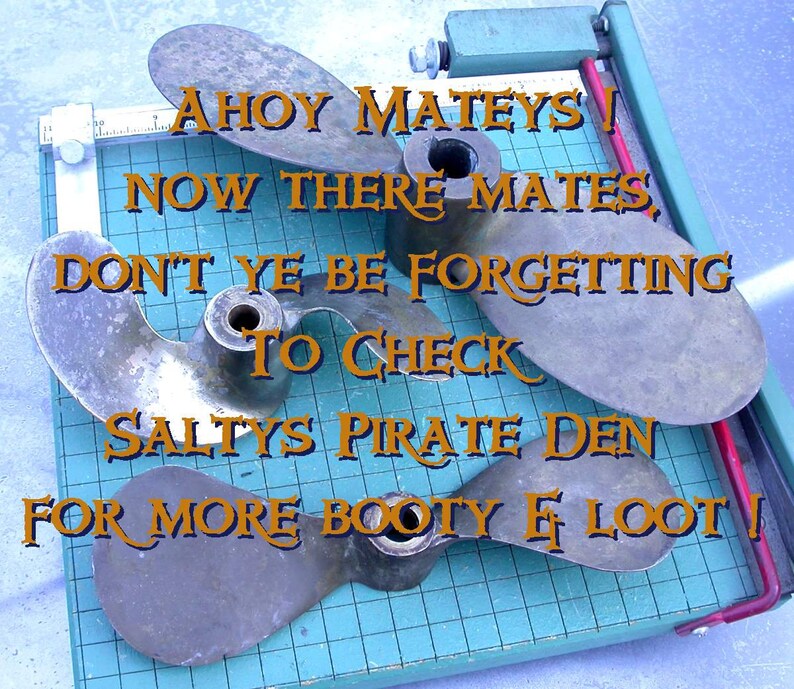 May include: Four bronze boat propellers on a blue and white grid surface. The propellers are arranged in a circle with the text "Ahoy Mateys! Now there mates, don't ye be forgetting to check Salty's Pirate Den for more booty & loot!" in orange text.