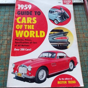 May include: A vintage 1959 "Guide to Cars of the World" book cover. The cover features a red sports car, along with images of other cars. The title is in large yellow letters on a red background. The book is published by Motor Trend.