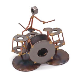 May include: A metal sculpture of a drummer playing a drum set. The drummer is made of wire and a nut for a head. The drums are made of washers and nuts.