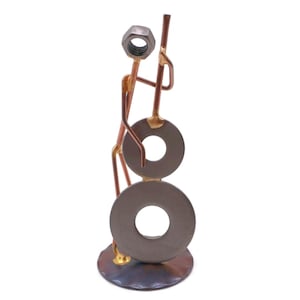 May include: A metal sculpture of a person playing a double bass. The sculpture is made of copper and silver colored metal and is about 10 inches tall.