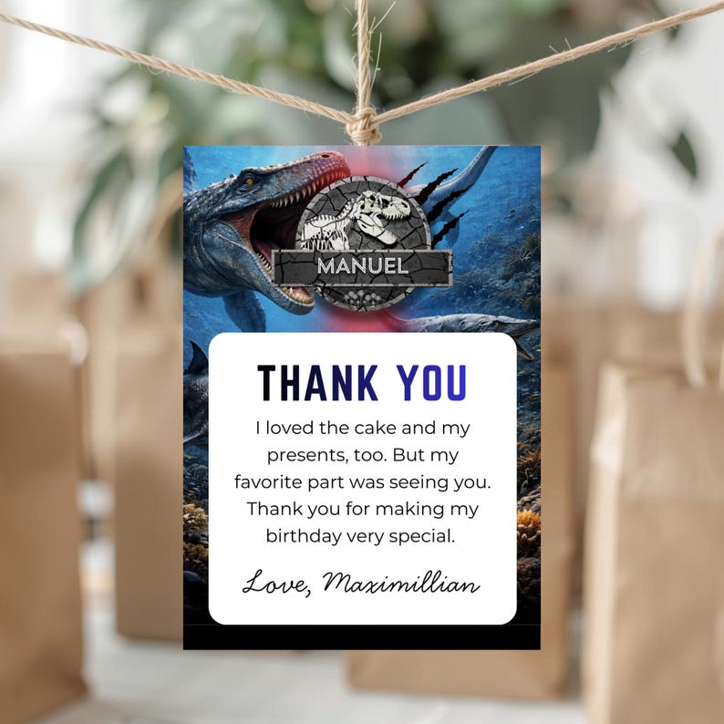 May include: A rectangular gift tag with a dinosaur theme. The top features a dinosaur illustration and the name "Manuel." Below, the tag reads "THANK YOU" and includes a personalized message. The tag is suspended by twine.