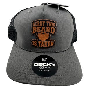 May include: Gray and black trucker hat with a brown leather patch that says "Sorry This Beard Is Taken". The hat has a black mesh back and a gray brim. The hat is a Deckys Classic Original.