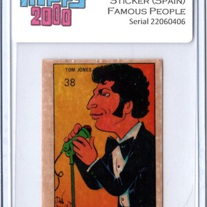 May include: A vintage Tom Jones sticker from the 1973 Hippy 2000 Famous People series, made in Spain. The sticker features a cartoon illustration of Tom Jones in a tuxedo, holding a microphone. The sticker is encased in a protective holder.