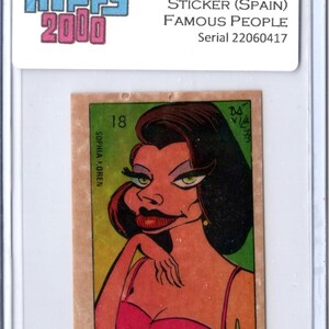 May include: A vintage 1973 Hippy 2000 sticker from Spain featuring a cartoon illustration of Sophia Loren. The sticker has a pink and red dress, black hair, and green eyes. The sticker is encased in a protective holder.