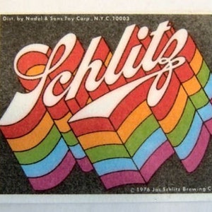 May include: A vintage Schlitz beer logo sticker with a rainbow design. The text "Dist. by Nadel & Sons Toy Corp., N.Y.C. 10003" and "1976 Jas Schlitz Brewing Co" are printed on the sticker.