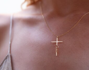 May include: A gold necklace with a delicate cross pendant. The cross has the name "Erica" inscribed on it.