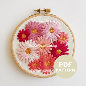 May include: A PDF pattern for embroidery featuring a hoop with pink and red flowers. The text "PDF PATTERN" is on a beige circle in the lower right corner.