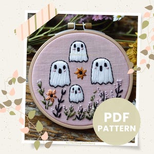 May include: A pink embroidery hoop with a design of four white ghosts and flowers. The hoop is on a wooden surface. The text "PDF PATTERN" is in the lower right corner of the image.