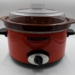 Może przedstawiać: Czerwony wolnowar Rival Crock-Pot z przezroczystą pokrywą i czarnymi uchwytami. Pokrętło sterowania ma ustawienia Wyłączone, Niskie i Wysokie. Na przodzie wydrukowano słowa "Crock-Pot" i "Removable Server".