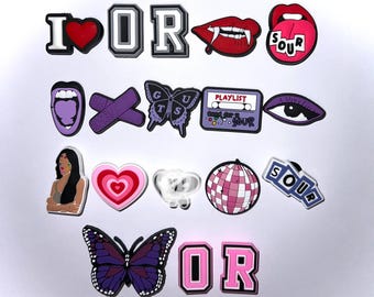 May include: A set of 15 colorful shoe charms featuring various designs, including hearts, butterflies, lips, a cassette tape, and the word "SOUR".