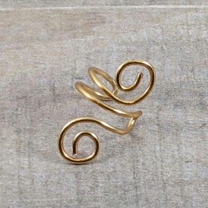 May include: A gold-colored ear cuff made of wire, with a double-spiral design.