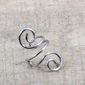 May include: Silver ear cuff with a double spiral design. The cuff is made of wire and is designed to wrap around the ear.
