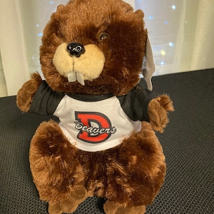 May include: Brown plush beaver wearing a black and white shirt with a red "D" and the word "Beavers" underneath.