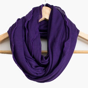 May include: A purple infinity scarf hanging on a wooden hanger.