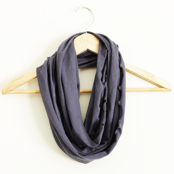 Peut inclure: Une écharpe grise en forme d'infini suspendue à un cintre en bois. L'écharpe est faite d'un tissu doux et extensible, parfait pour ajouter une touche de chaleur et de style à n'importe quelle tenue.