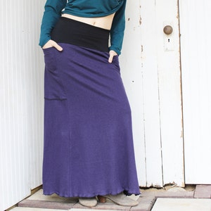 May include: A long purple skirt with a black waistband and a pocket on the left side.