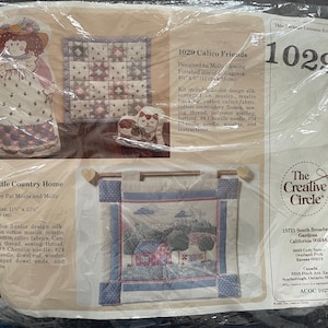 May include: A craft kit package featuring three different designs: a doll, a quilt square, and a landscape scene. The package includes the text "1029 Calico Friends" and "1030 Little Country Home". The Creative Circle logo is also visible.