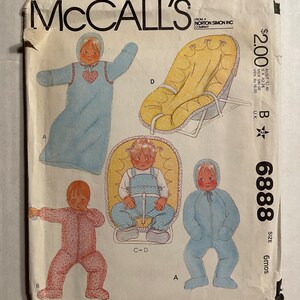 May include: A sewing pattern for a baby's outfit and a baby seat. The pattern is from McCall's and is size 6 months. The pattern includes a blue sleeper, a pink sleeper, and a yellow baby seat.