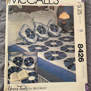 May include: McCall's sewing pattern envelope featuring a bedspread and pillow set. The design includes a quilt with blue and white circular patterns, matching pillows, and a bed with a lamp. The envelope has the text "McCall's" and "Yours Truly for McCall's".