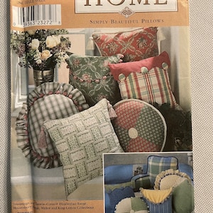 May include: Simplicity Home sewing pattern number 8859 for simply beautiful pillows. The pattern shows a variety of pillows in different colors and patterns, including red, green, white, and blue. The pillows are made with a variety of fabrics, including plaid, floral, and solid colors.
