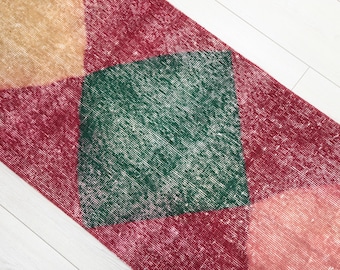 May include: A rectangular rug with a patchwork design. The rug features a combination of colors, including red, green, and tan. The rug is placed on a white wooden floor.