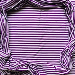 Könnte beinhalten: Ein Stoff mit horizontalen weißen und lila Streifen. Der Stoff ist an den Rändern drapiert und bildet einen Rahmen. Die Streifen sind gleichmäßig verteilt und verlaufen über die gesamte Oberfläche.