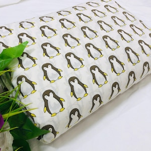 Può includere: Tessuto bianco con un motivo ripetuto di pinguini dei cartoni animati. Ogni pinguino ha un corpo marrone, pancia bianca e piedi gialli. Il tessuto è piegato, mostrando la continuità del motivo. Il tema è giocoso e adatto agli articoli per bambini.