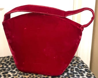 Può includere: Una borsa a mano in velluto rosso vivo con un'unica maniglia superiore.