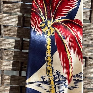 Può includere: Una cravatta di seta con un design tropicale. La cravatta presenta una grande palma rossa e bianca su sfondo blu navy. Una scena di spiaggia si trova nella parte inferiore della cravatta.