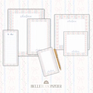 May include: A collection of stationery items, including notepads and a to-do list, featuring a delicate bow and ribbon design in pastel pink and blue. The name "chelsea" is printed on several items. A gold pen rests on the surface.