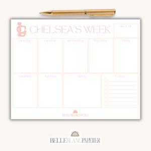 Könnte beinhalten: Ein Wochenplaner-Notizblock mit dem Text "CHELSEA'S WEEK" in rosa Schrift. Der Notizblock hat Abschnitte für jeden Wochentag, Notizen und Aufgaben. Ein goldener Stift liegt obenauf. Der Notizblock ist von BELLEBLANCPAPIER.