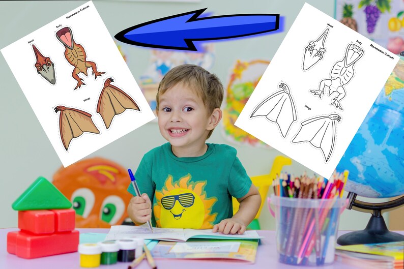 May include: A young child smiles while sitting at a desk with art supplies. Two sheets of paper with dinosaur illustrations are on the desk. One sheet is colored, and the other is a black and white outline. The child is wearing a green shirt with a sun graphic.