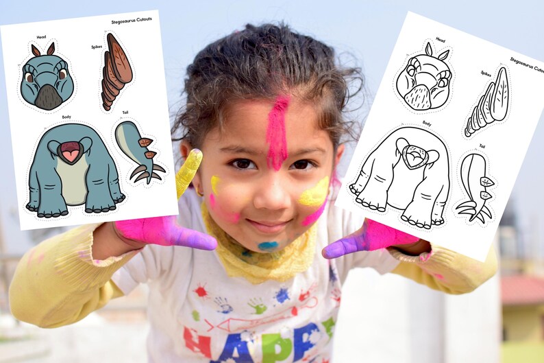 May include: Two sheets of Stegosaurus Cutouts are held up by a child with colorful face paint. The cutouts feature a blue and gray dinosaur with labeled parts: head, spike, body, and tail. The text "Stegosaurus Cutouts" is at the top.