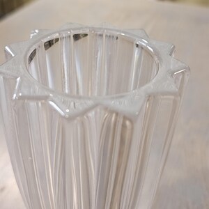 Pu&ograve; includere: Vaso di vetro trasparente con bordo a forma di stella. Il vaso presenta dettagli verticali e scanalati, creando una superficie strutturata. Il design &egrave; semplice ed elegante, adatto per esporre fiori o come elemento decorativo.