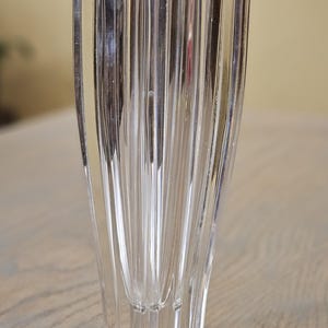 Pu&ograve; includere: Un vaso di vetro trasparente scanalato con un design geometrico unico. Il vaso ha una forma rettangolare con scanalature verticali, creando una superficie strutturata. La base ha una forma a stella. Il vaso &egrave; alto circa 15 cm.