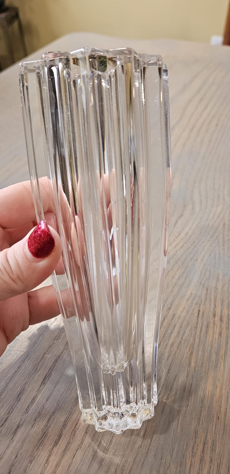 Pu&ograve; includere: Vaso di vetro trasparente con design a coste verticali. Il vaso ha una forma rettangolare con base svasata e parte superiore leggermente pi&ugrave; ampia. Il vaso &egrave; tenuto in mano con smalto rosso glitterato.