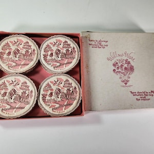 May include: A set of four round coasters with a pink and white Willow Ware pattern featuring pagodas and birds, housed in a square box. The box lid displays the text Willow Ware and the phrase There is always a slip between the cup and the lip.