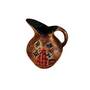 Puede incluir: Una pequeña jarra de cerámica con acabado marrón texturizado e interior negro. El exterior presenta un gráfico pintado a mano de un molino de viento con detalles en rojo, verde y negro. La jarra tiene un asa curva y un pico vertedor puntiagudo.