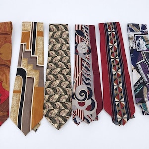 Könnte beinhalten: Sechs Krawatten in einer Reihe angeordnet. Die erste ist orange und rot mit einem Sonnen- und Tiermotiv. Die zweite zeigt geometrische Formen in Beige und Braun. Die dritte hat ein sich wiederholendes Blattmuster. Die vierte zeigt graue Wirbel. Die fünfte ist rot mit einem Rautenmuster. Die sechste ist blau und weiß mit einer Collage aus verschiedenen grafischen Bildern.